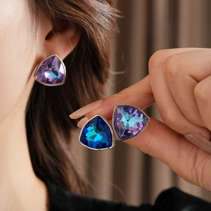 Détail de boucles d'oreilles triangles en cristal étincelant violet et bleu sur mannequin