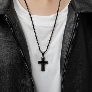 Close-up of a black titanium steel cross pendant necklace worn with a black leather jacket