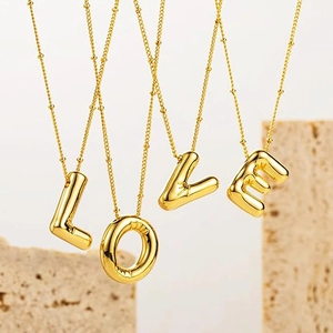 Detailed view of four golden balloon-style letter pendants spelling LOVE on beaded chains