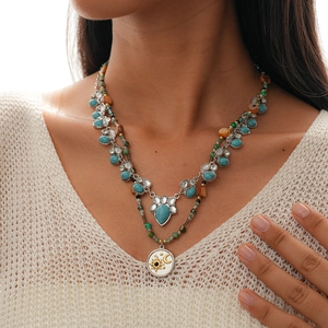 Detail of layered turquoise gemstone necklaces with silver sun and moon pendant engraving