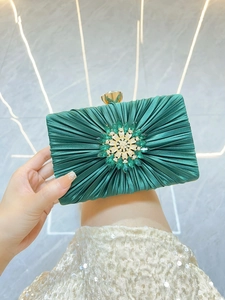Detail der dunkelgrünen Seiden-Abendtasche mit Plissee-Struktur und Smaragd-Blumenschließe