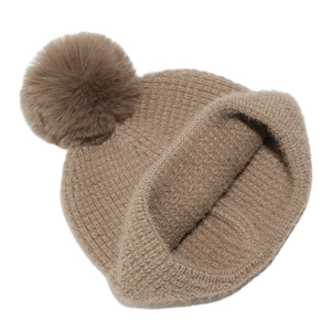 Detail of light brown waffle knit beanie with fluffy faux fur pompom and soft plush texture