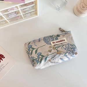 Close-up of floral embossed fabric pouch with vintage patterns and secure metal zipper