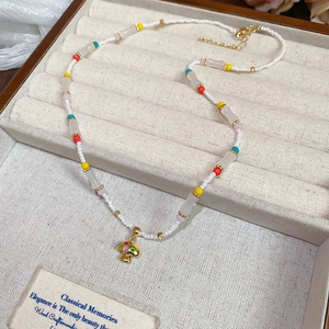Detail of beaded necklace with golden mushroom pendant on a linen jewelry tray
