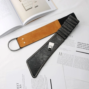 Detail of a punk style wide elastic belt featuring metal studs and a large round ring buckle