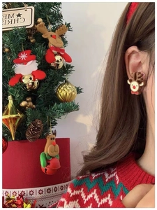 Gros plan de boucles d'oreilles renne de Noël portées avec un sapin festif en fond
