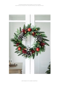 Close-up of Christmas wreath with pine needles, red berries, cones and warm LED lights