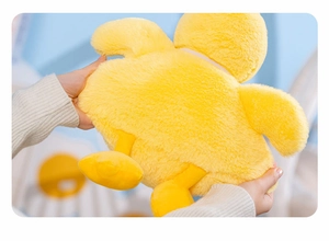 Close-up of soft yellow plush duck toy held in hands showing fluffy texture and bow detail