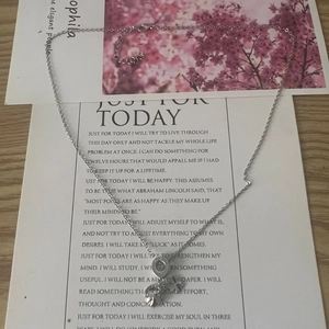 Detail of silver clover and ring pendant necklace on a decorative card background