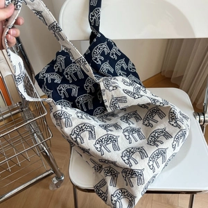 Detail of canvas tote bags featuring repeat sheep patterns in navy and cream white