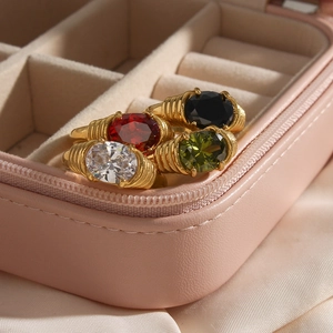 Close-up of four gold stainless steel rings with oval stones in a pink jewelry box