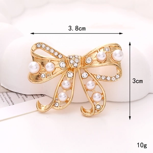 Detail view of a 3.8cm gold bow brooch with white pearls and sparkling rhinestones