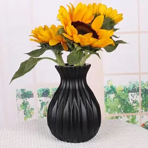 Nordic black round plastic vase with vertical ribbed texture and yellow sunflowers