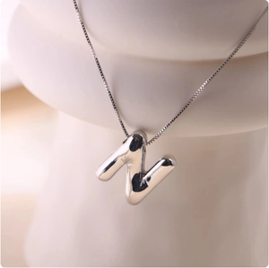 Detailed close-up of a polished silver balloon letter N pendant on a fine box chain