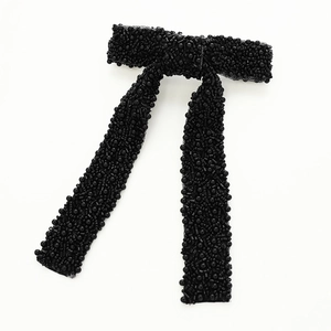 Detailed view of handcrafted black beaded bow hair clip with elegant long ribbon tails