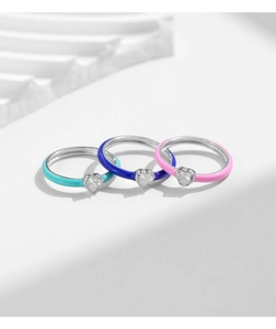 Close-up of three enamel rings in pink and blue with heart-shaped white zircons