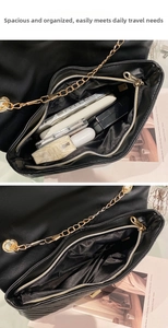 Detail showing high-capacity black quilted crossbody bag with golden chain and phone