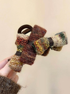 Gros plan sur un chouchou nœud en tweed multicolore avec un élastique marron chaud
