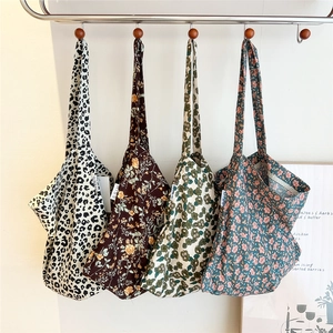 Minimalist cotton tote bags in leopard and floral patterns shown hanging on hooks