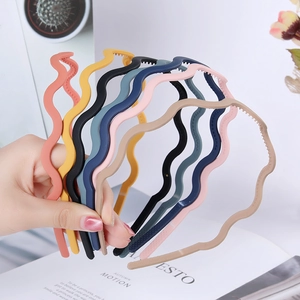 Detailed view of six colorful wavy hairbands in orange, yellow, black, navy, pink, and beige