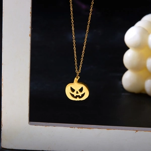 Artistic close-up of a gold pumpkin pendant necklace hanging in a vintage wooden frame