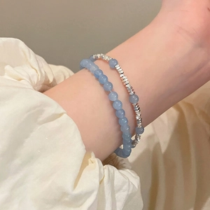 Détail de bracelets superposés en perles d'aigue-marine et perles métalliques argentées