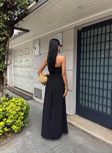 Rear view of a black strapless maxi dress featuring a slim waist and flowing drape detail