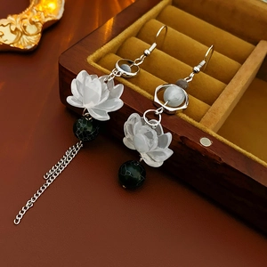 Macro detail of lotus earrings with green beads on a vintage velvet jewelry box
