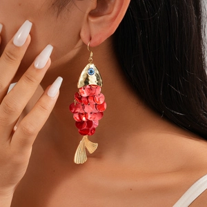 Exaggerated red sequin fish fringe earrings with golden metal details on model