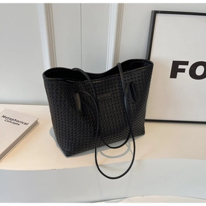 Detail of premium black woven tote bag with high-quality faux leather texture and handles