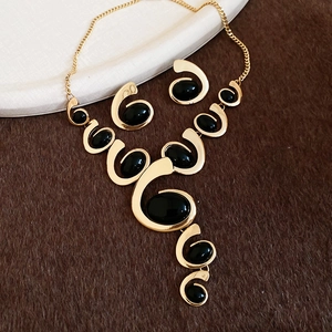 Detailed shot of golden metal tassel necklace and earrings set with black oval gemstone