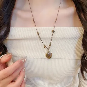 Collana con ciondolo a cuore in occhio di tigre indossata da una modella con top bianco