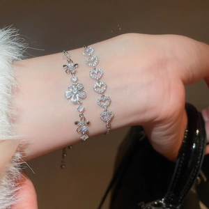 Gros plan sur l'ensemble de bracelets à breloques fleur en zircon et cœur évidé au poignet