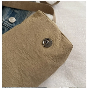 Close-up of khaki textured fabric bag featuring a round metallic M FASHION logo plaque