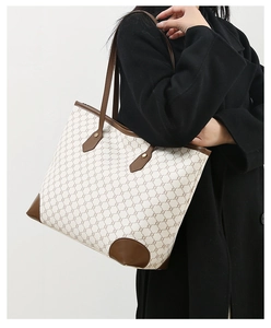 Detailed view of women's tote bag with vintage pattern and brown leather straps on model