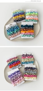 Detail of satin scrunchies set on white display card in minimalist ceramic tray