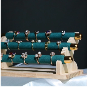 Detailed side view of three-tier green velvet ring display stand with wooden base