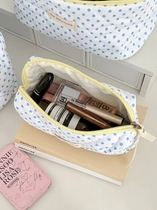 Detail of quilted cosmetic bag with blue dots showing spacious storage for makeup items