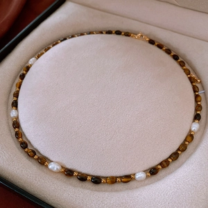 Détail macro de perles d'eau douce et de perles œil de tigre sur collier doré
