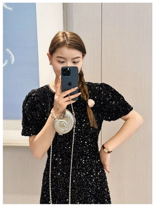 Mini silver conch hard shell clutch bag with pearl chain shown on black sequin dress