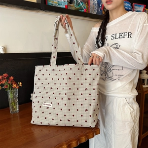 Détail du sac cabas en toile avec pois rouges et broderies nœuds dans un cadre chaleureux