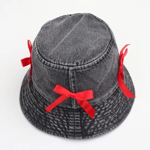 Detail of red satin bows on a dark gray washed denim bucket hat with cotton texture
