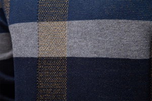 Vue macro de la texture du tricot bleu marine et du motif à carreaux classique sur le pull