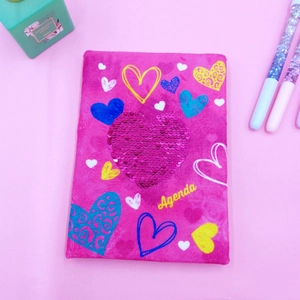 Close-up of pink plush notebook cover featuring a 3D sequin heart and colorful motifs
