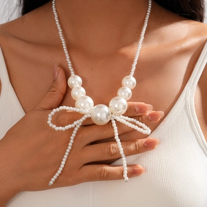 Close-up of elegant faux pearl necklace featuring a large bow pendant on a female model