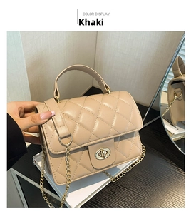 Detail of khaki quilted crossbody bag with metal lock and chain strap on hand