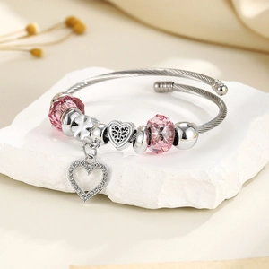 Close-up of silver steel heart bracelet with pink crystal beads on white stone base