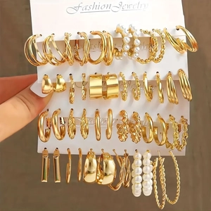 Primo piano di set di orecchini dorati con perle in vari design a cerchio e bottone