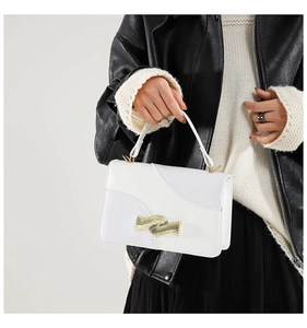 Detail of white square handbag showing crocodile texture and wavy gold metal buckle