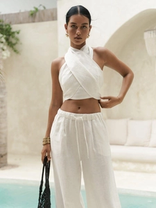 Detail of white cross halter top and wide-leg trousers in breathable linen fabric